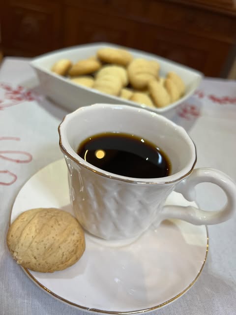 Bolachinha sólida de polvilho doce ao lado de uma xícara de café, com outras bolachinhas ao fundo